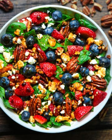 strawberry spinach salad with blueberries, pecans, feta cheese, and balsamic glaze in a bowl