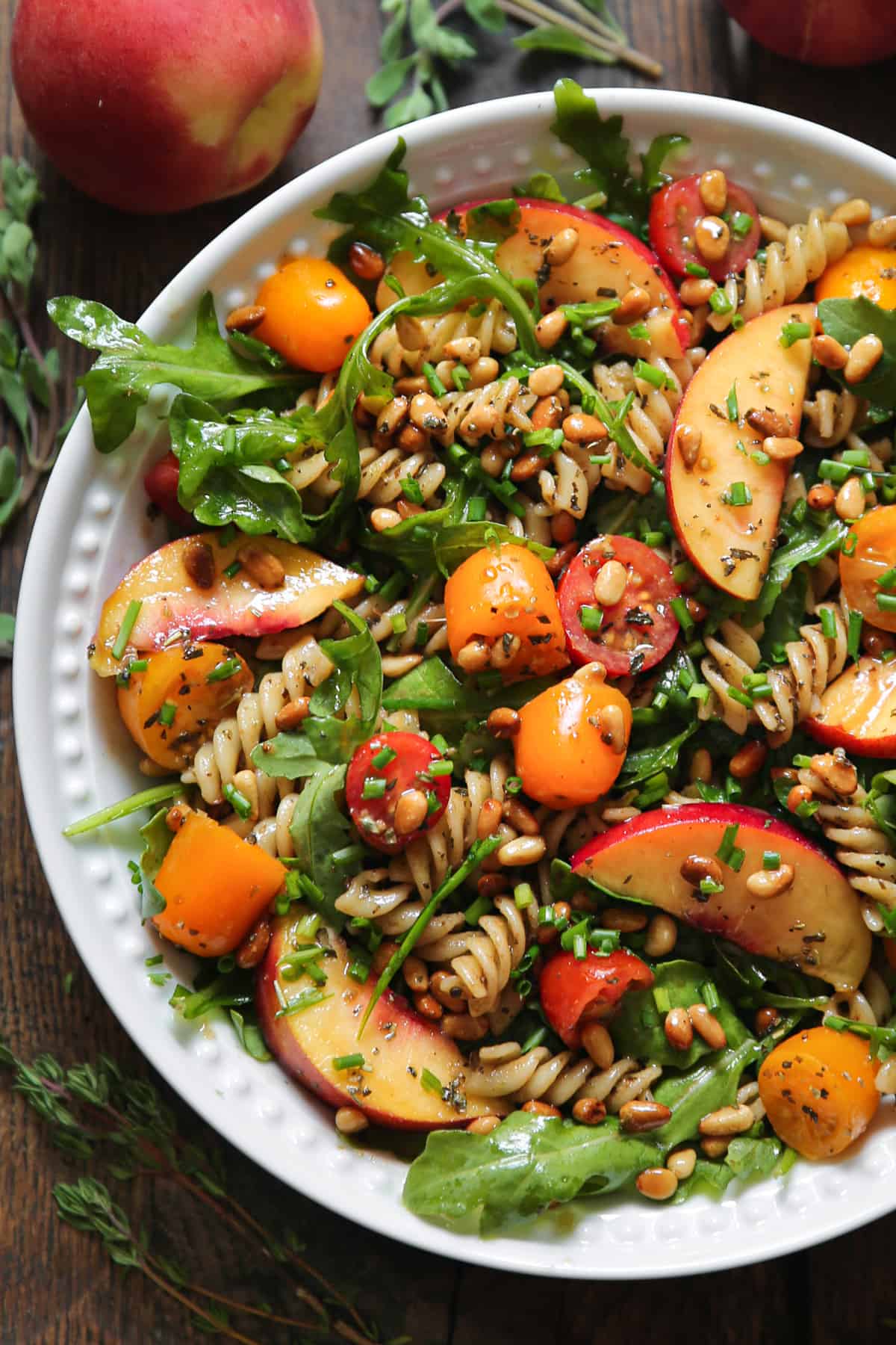 Peach Pasta Salad with Arugula, Tomatoes, and Pine Nuts in a bowl