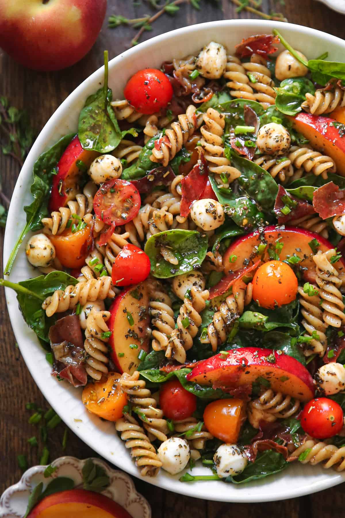 Summer Pasta Salad with Peaches, Spinach, Tomatoes, and Mozzarella Cheese in a bowl