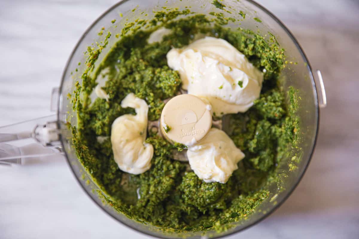 blended basil pesto ingredients with olive oil and mayonnaise in food processor