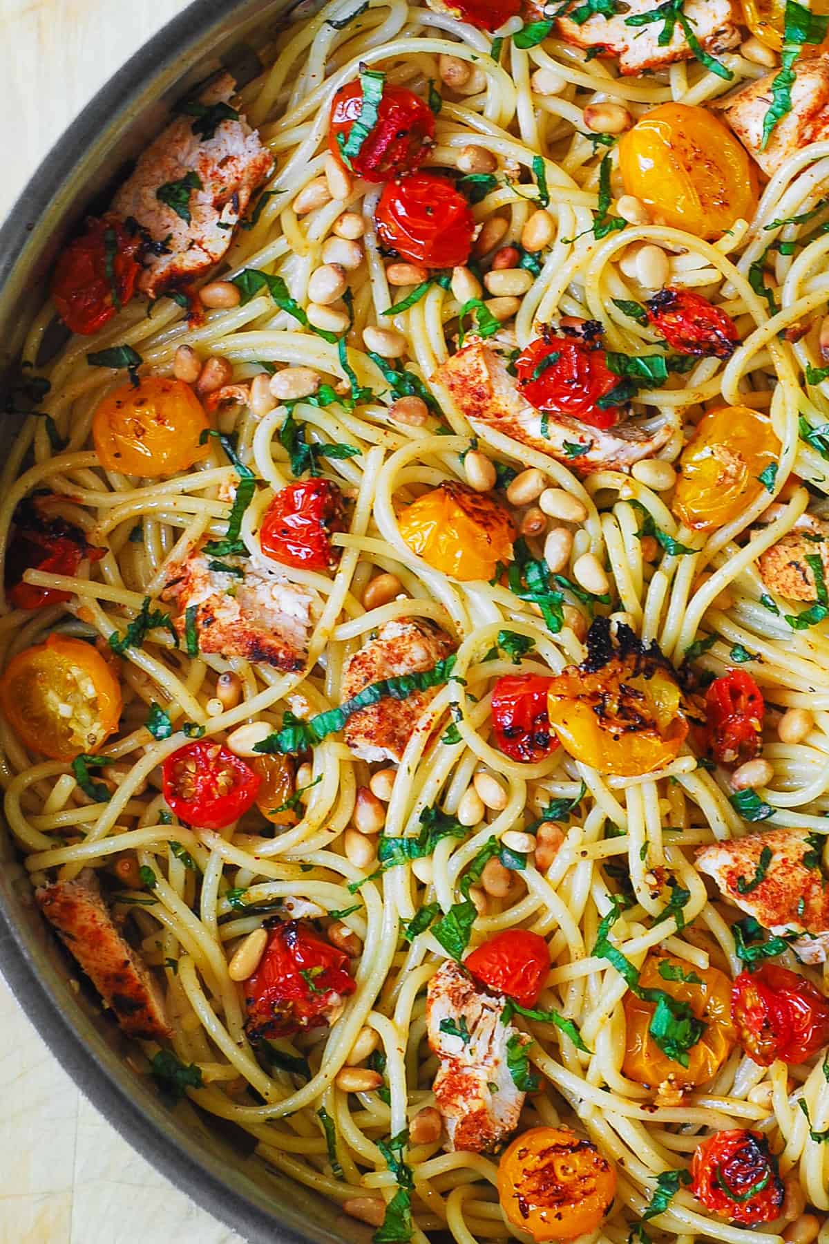 pasta with roasted cherry tomatoes, chicken, pine nuts, and lemon garlic butter sauce in a stainless steel pan