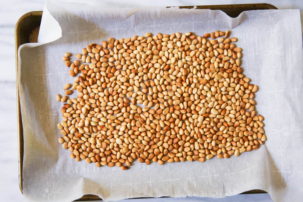 toasted pine nuts on parchment paper lined baking sheet
