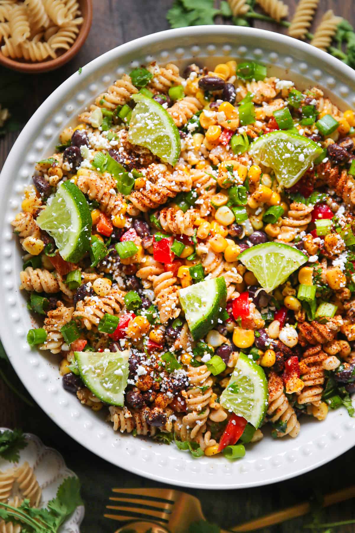 Mexican Street Corn Pasta Salad with slices of lime in a white bowl