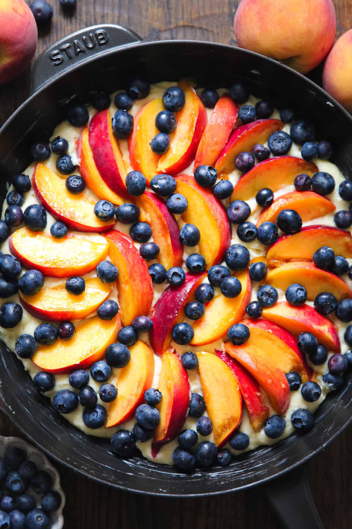 cake batter with fresh Peaches and blueberries in a cast iron skillet