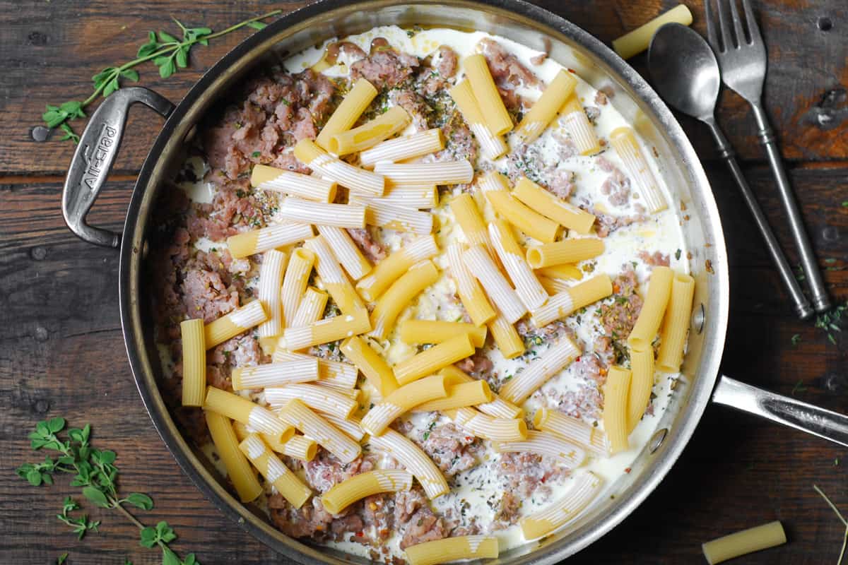 heavy cream, cooked sausage and uncooked rigatoni in a stainless steel skillet.