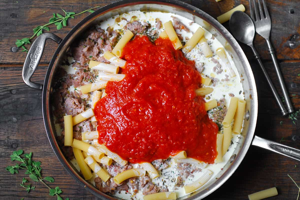 heavy cream, tomato sauce, cooked sausage and uncooked rigatoni in a stainless steel skillet.