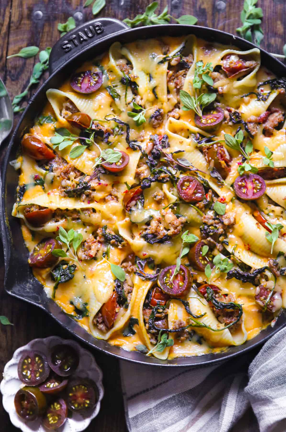 butternut squash stuffed pasta shells with sausage and topped with cheese in a cast iron skillet.
