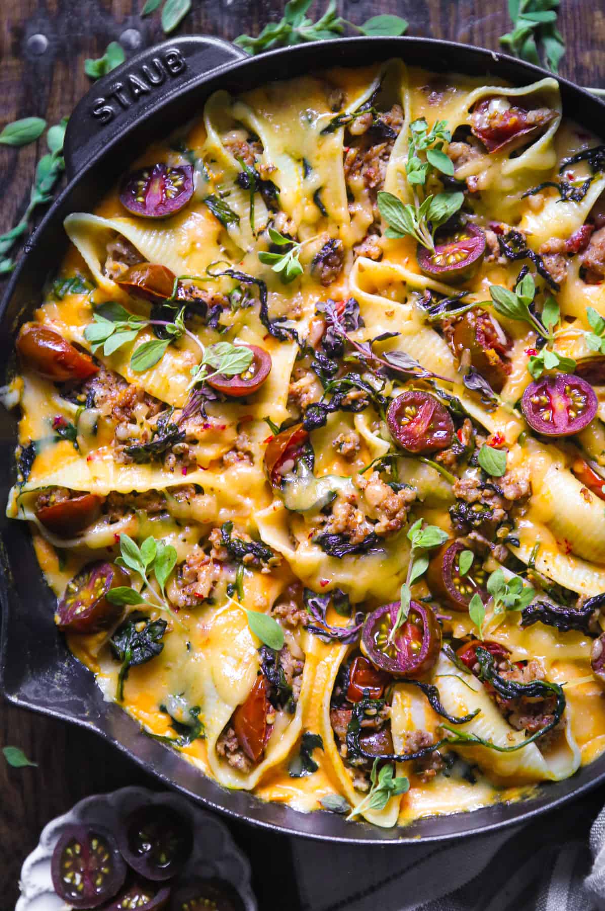 butternut squash stuffed pasta shells with sausage and topped with cheese in a cast iron skillet.