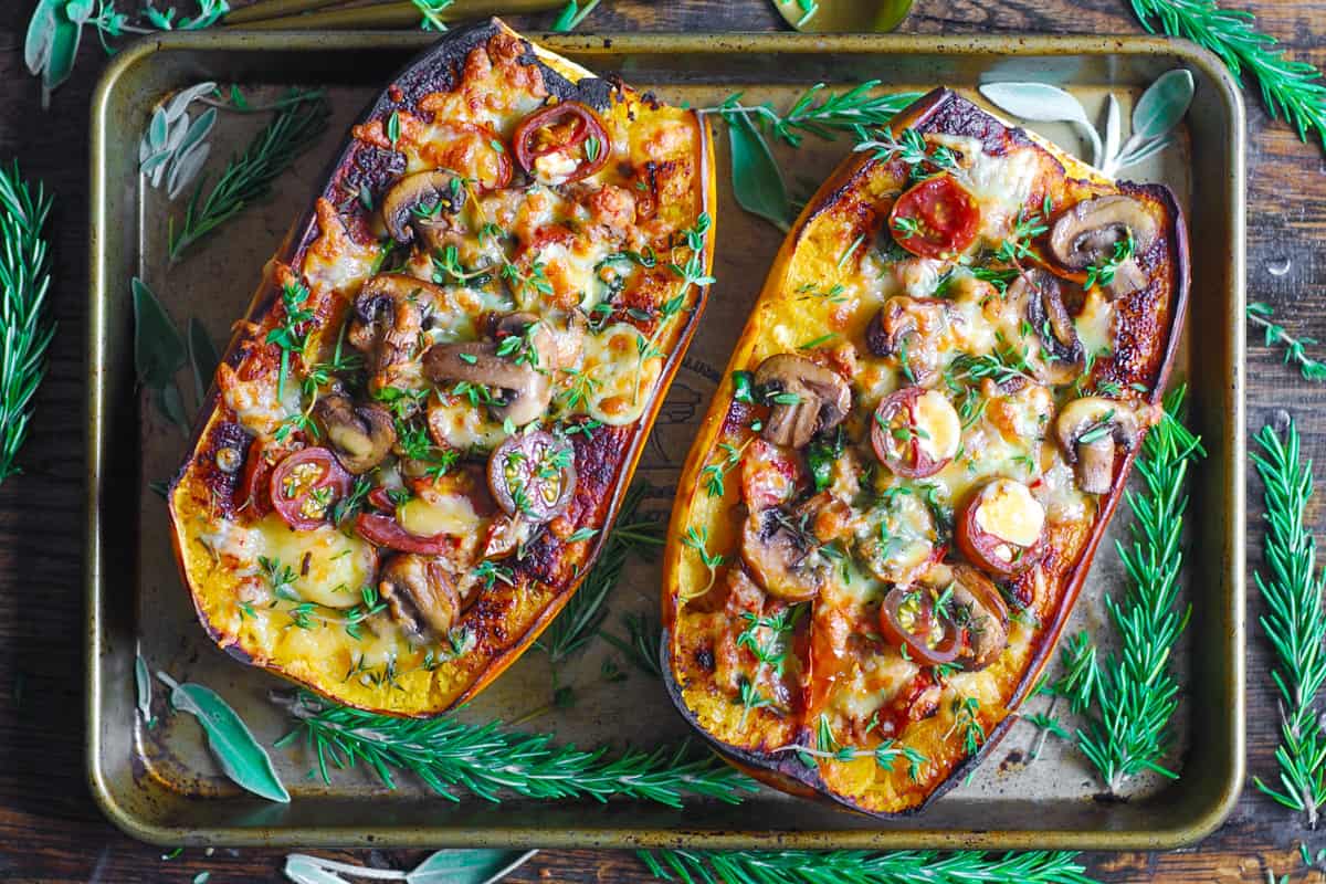 stuffed spaghetti squash with sausage, spinach, mushrooms, Parmesan cheese on a baking sheet.