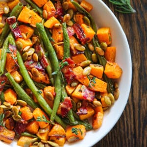 Roasted Veggies (Green Beans and Butternut Squash) with Bacon and Pumpkin Seeds - in a white bowl.