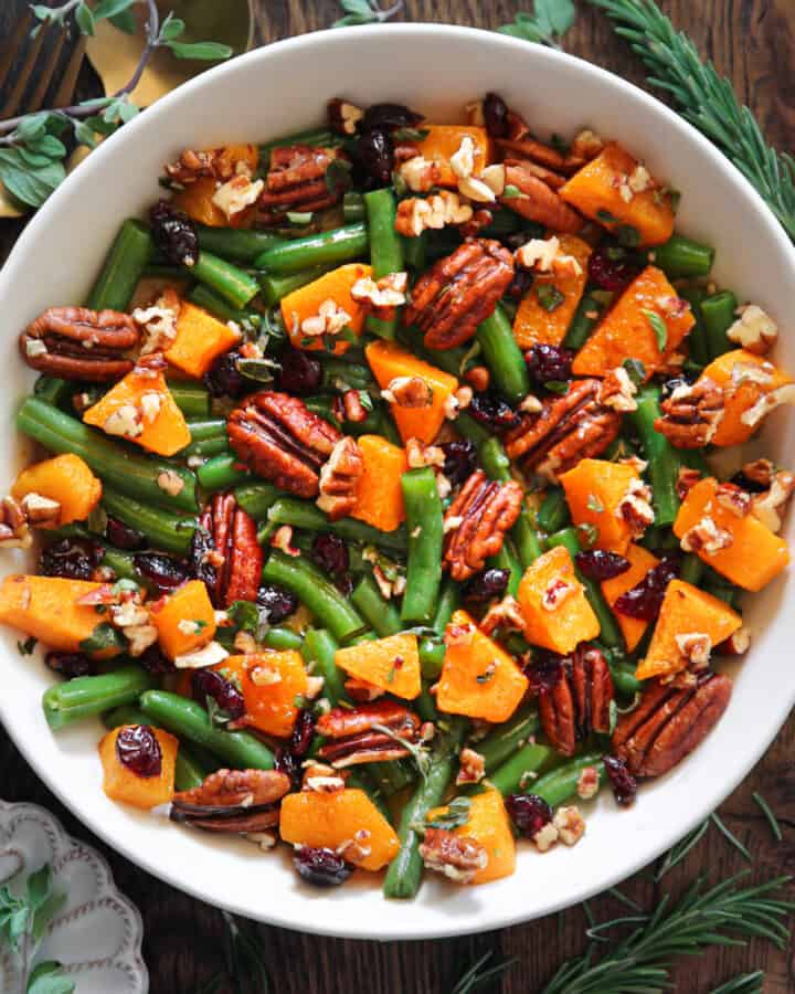 Thanksgiving Green Beans with Butternut Squash, Pecans, and Cranberries in a white bowl.