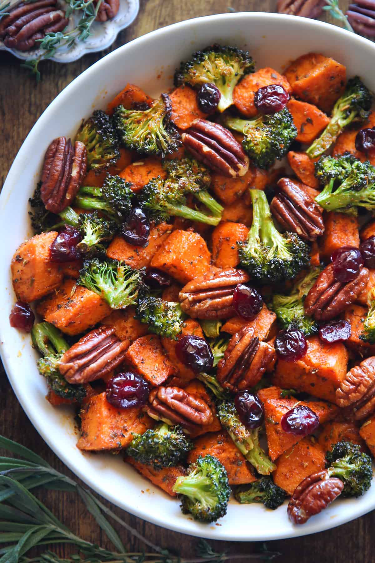 sweet potatoes and broccoli with pecan and cranberries in a white bowl.