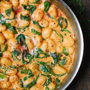 creamy spinach gnocchi in a stainless steel pan.