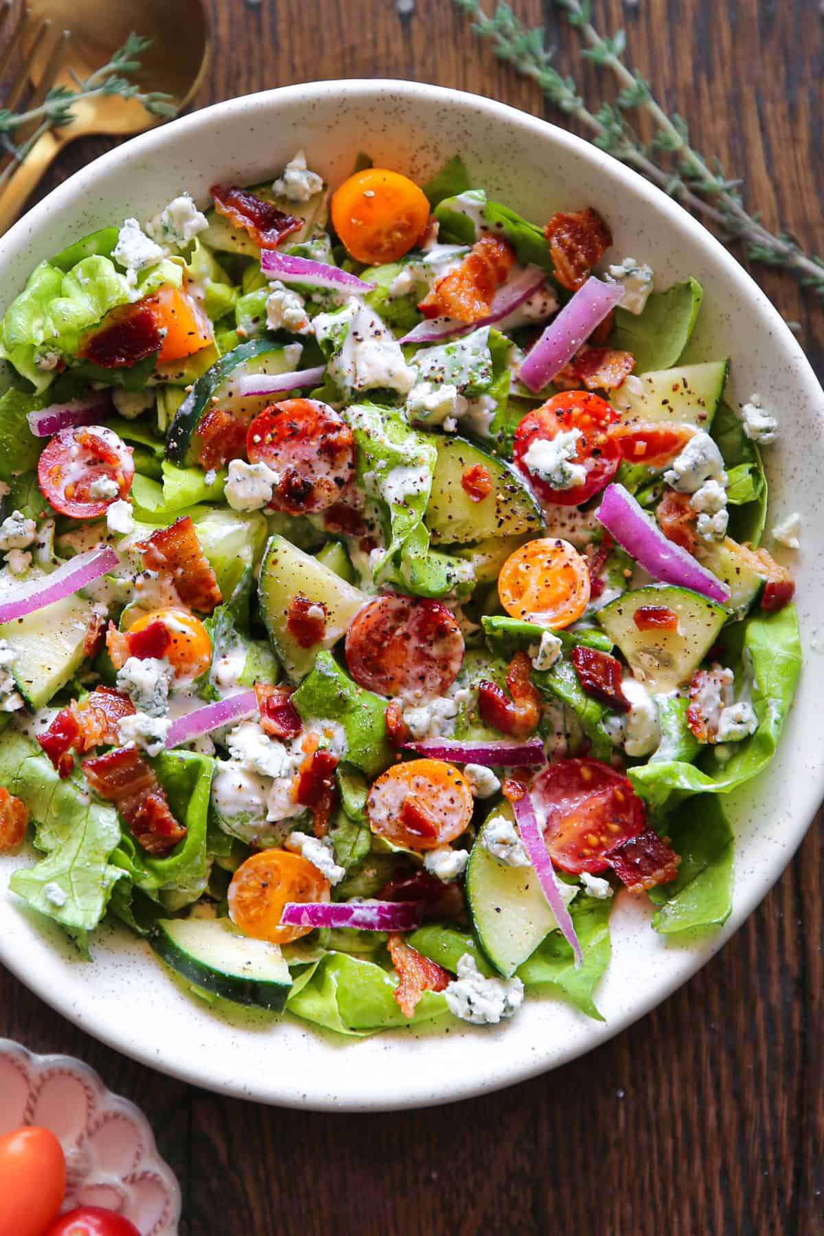 Tomato Cucumber Lettuce Salad with Bacon and homemade Blue Cheese Dressing - in a white bowl.