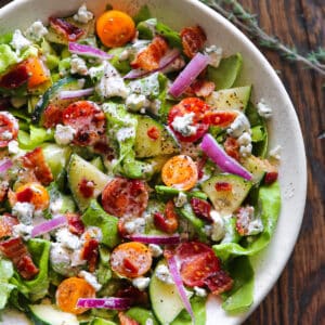 Tomato Cucumber Lettuce Salad with Blue Cheese Dressing - in a white bowl.