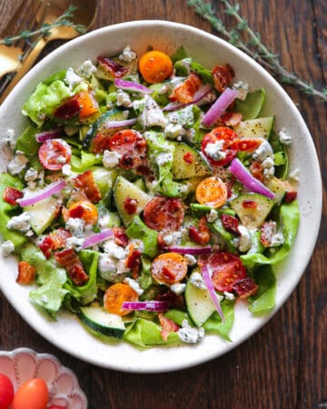 Tomato Cucumber Lettuce Salad with Blue Cheese Dressing - in a white bowl.