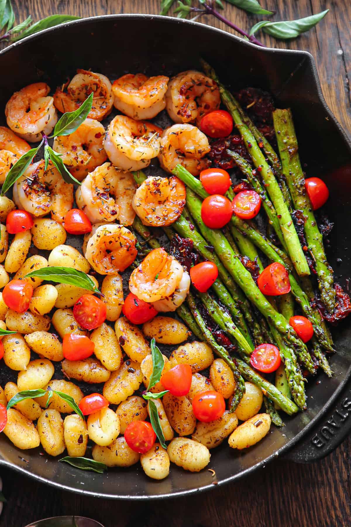 Shrimp Gnocchi with Asparagus, Sun-Dried Tomatoes, Cherry Tomatoes - in a cast iron skillet.