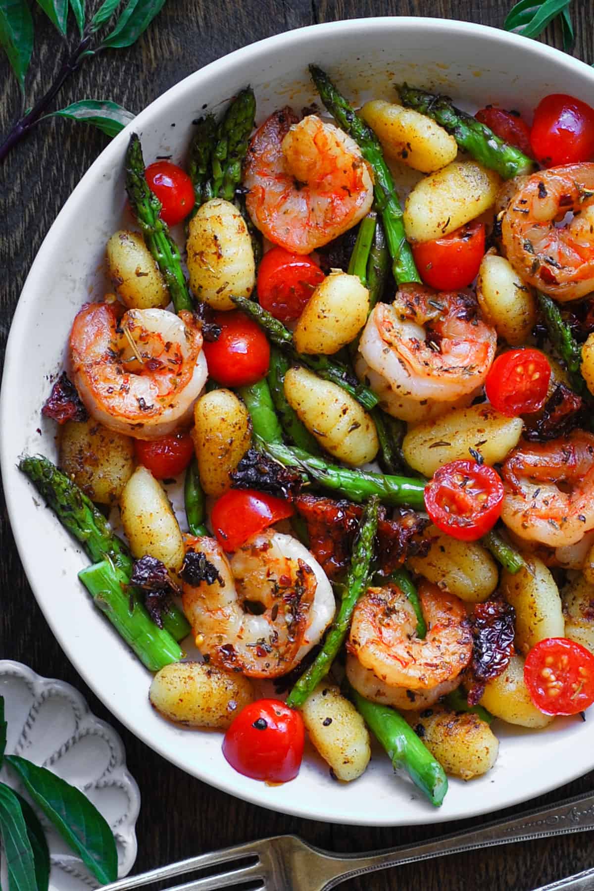 Shrimp Gnocchi with Asparagus, Sun-Dried Tomatoes, Cherry Tomatoes - in a white bowl.