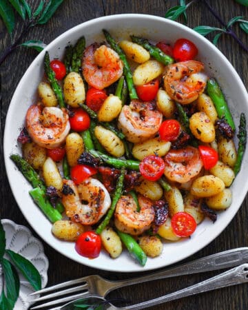 Shrimp Gnocchi with Asparagus, Sun-Dried Tomatoes, Cherry Tomatoes - in a white bowl.