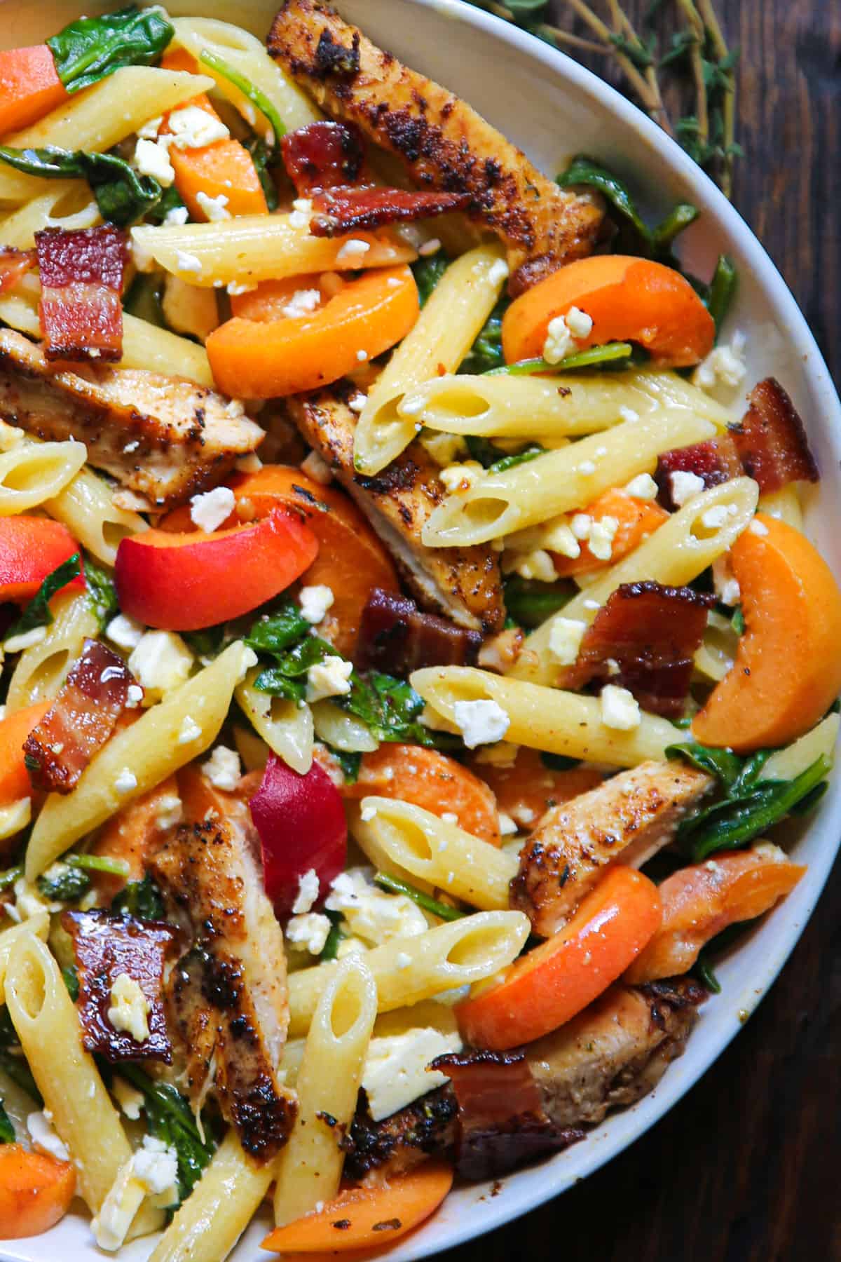Chicken Pasta Salad with Apricots, Spinach, Bacon, Feta, and the homemade Honey Dijon Mustard Lemon Dressing - in a white bowl.