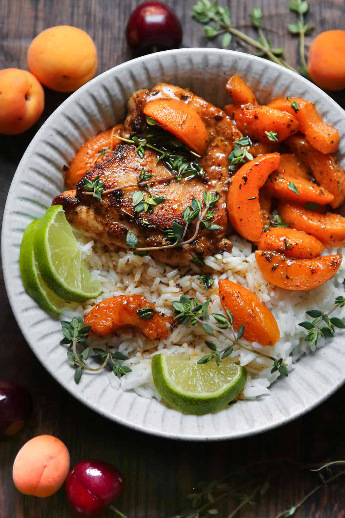 Chicken with cooked sliced Apricots, Honey-Lime Sauce, white rice, garnished with lime slices - on a white plate.