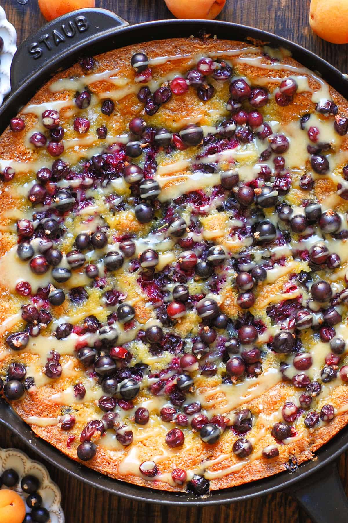 Black Currant Cake topped with fresh black currants and drizzled with maple cream - in a cast iron skillet.