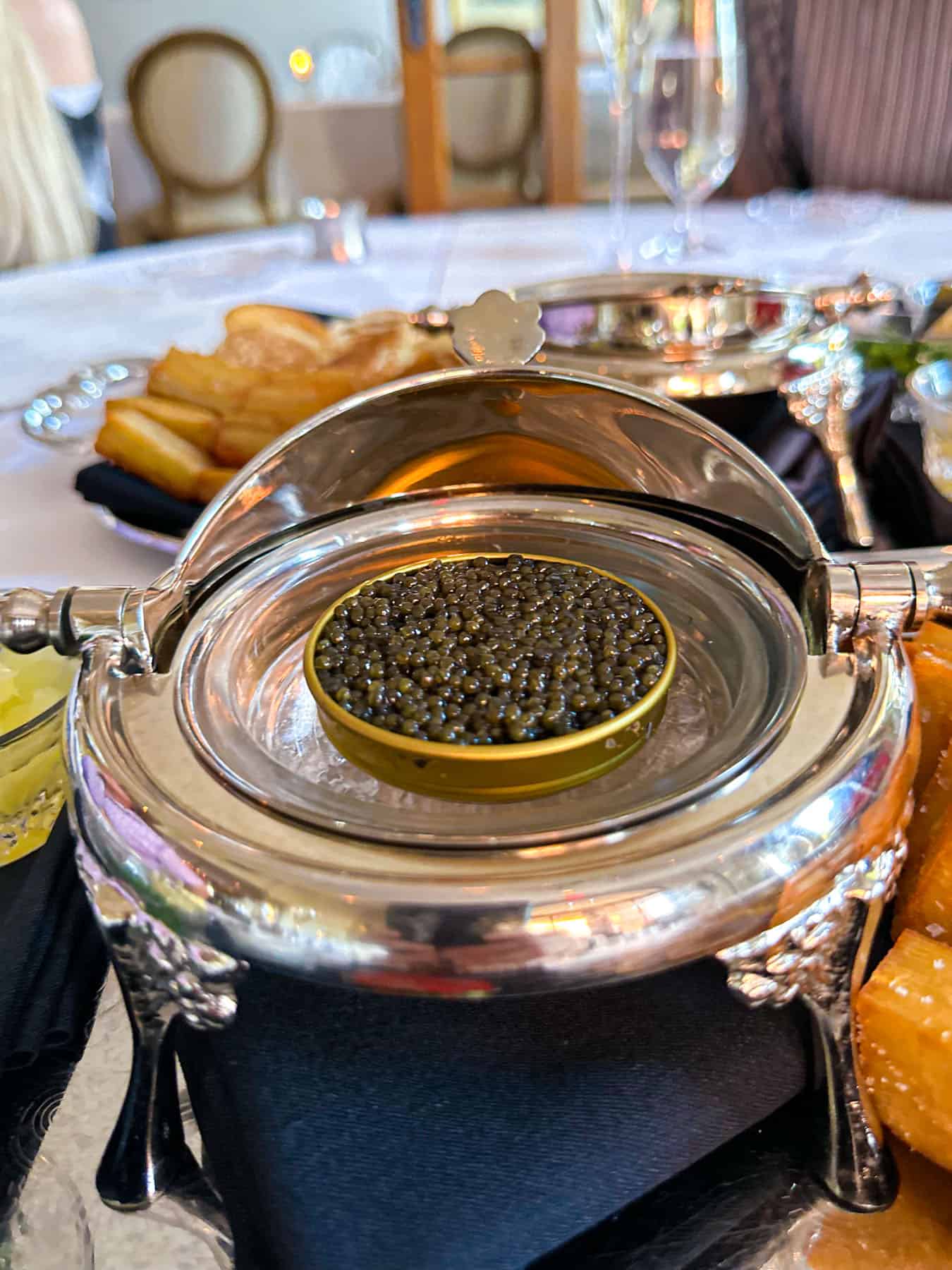 an opened jar of caviar and side dishes on a white table at Cafe Monarch in Scottsdale AZ.