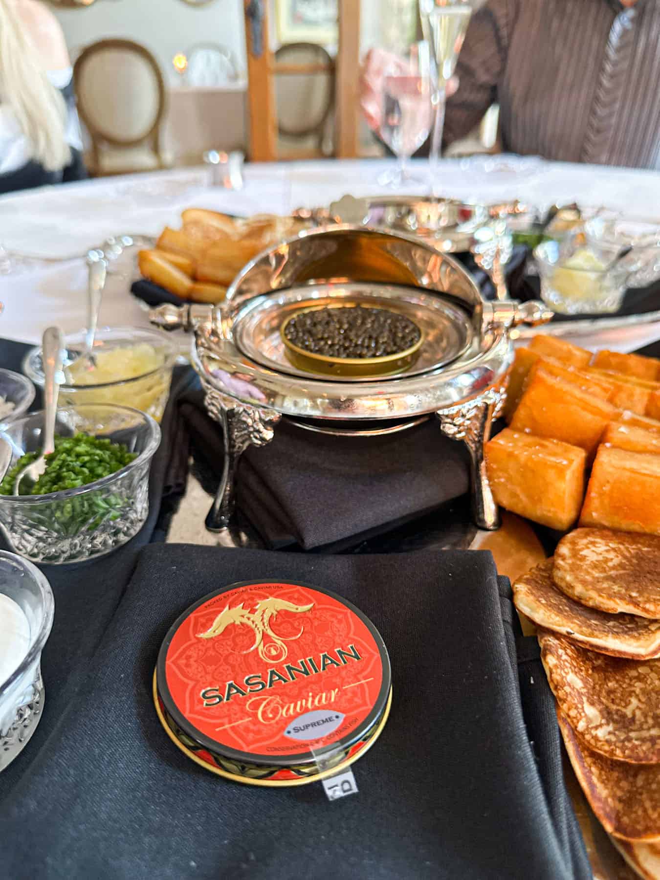 an opened jar of caviar and side dishes on a white table at Cafe Monarch in Scottsdale AZ.