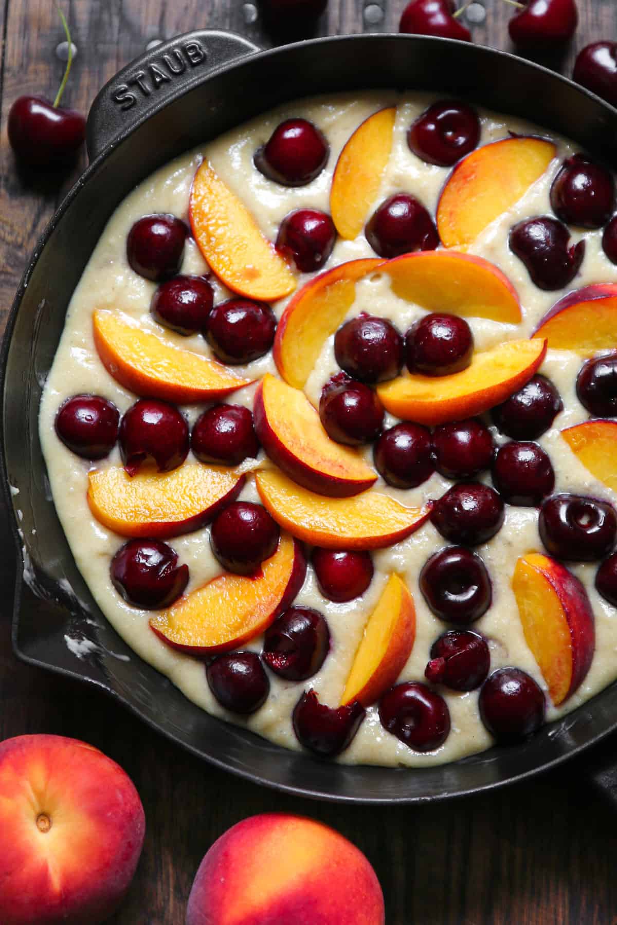 Fresh cherries and peaches on top of the raw cake batter in a cast iron skillet.