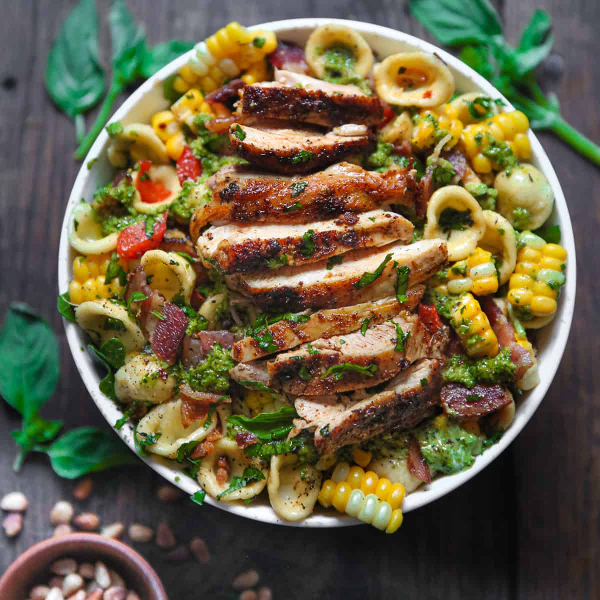 Chicken and Corn Pasta Salad with Bacon, Bell Peppers, and Creamy Basil Pesto Dressing - in a white bowl.