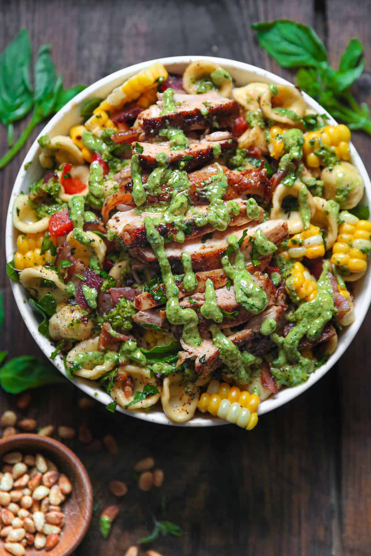 Chicken and Corn Pasta Salad with Bacon, Bell Peppers, and Creamy Basil Pesto Dressing - in a white bowl.