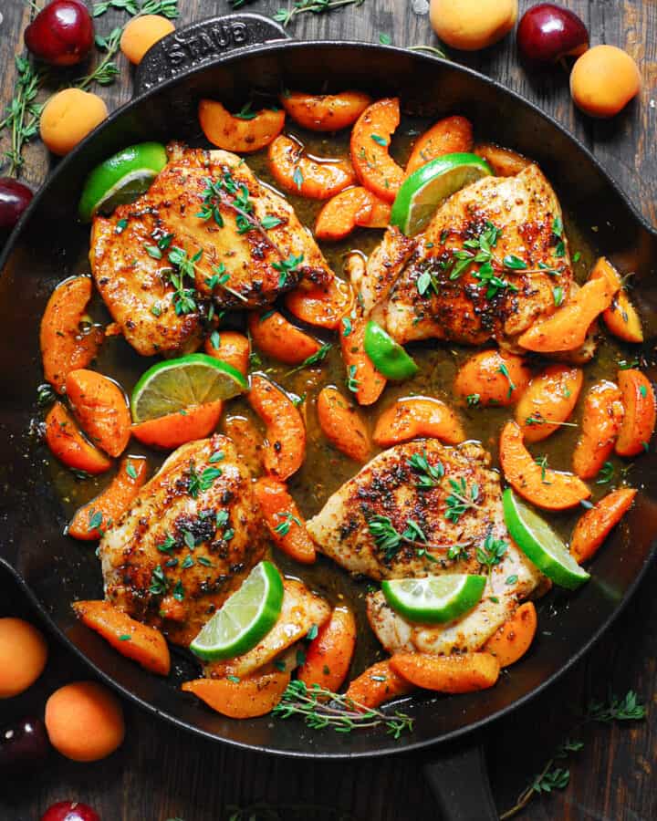 Chicken with cooked sliced Apricots, Honey-Lime Sauce, garnished with lime slices - in a cast iron skillet.