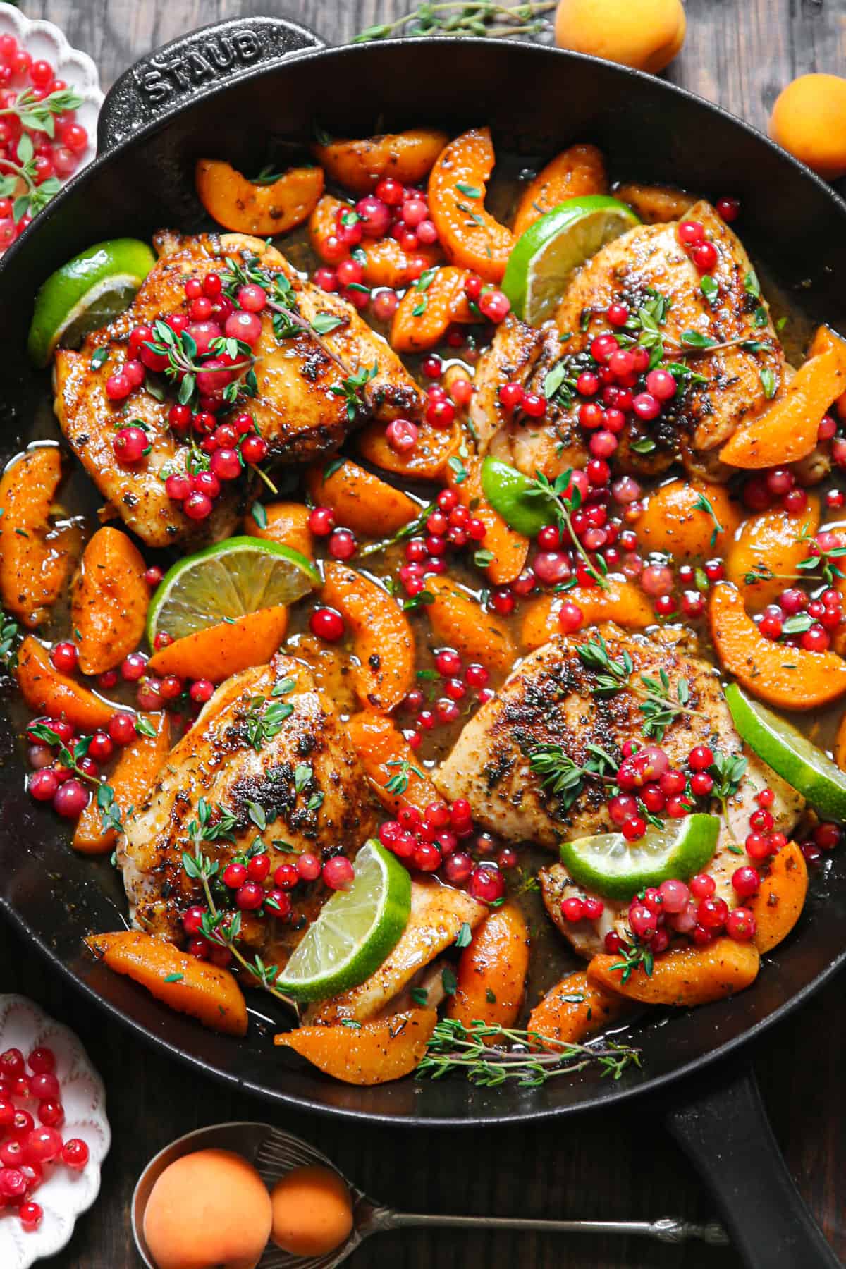 Seared Chicken Thighs with Red Currants, Apricots, Honey-Lime Sauce, garnished with lime slices - in a cast iron skillet.