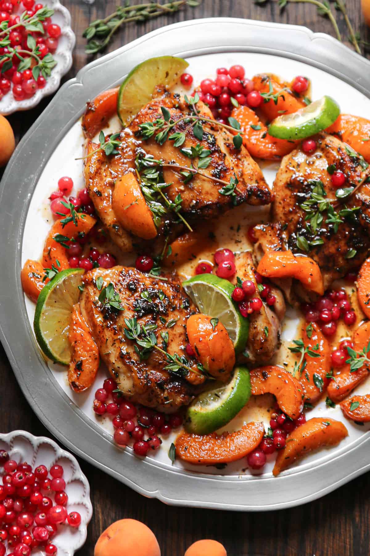 Seared Chicken Thighs with Red Currants, Apricots, Honey-Lime Sauce, garnished with lime slices - on a plate.