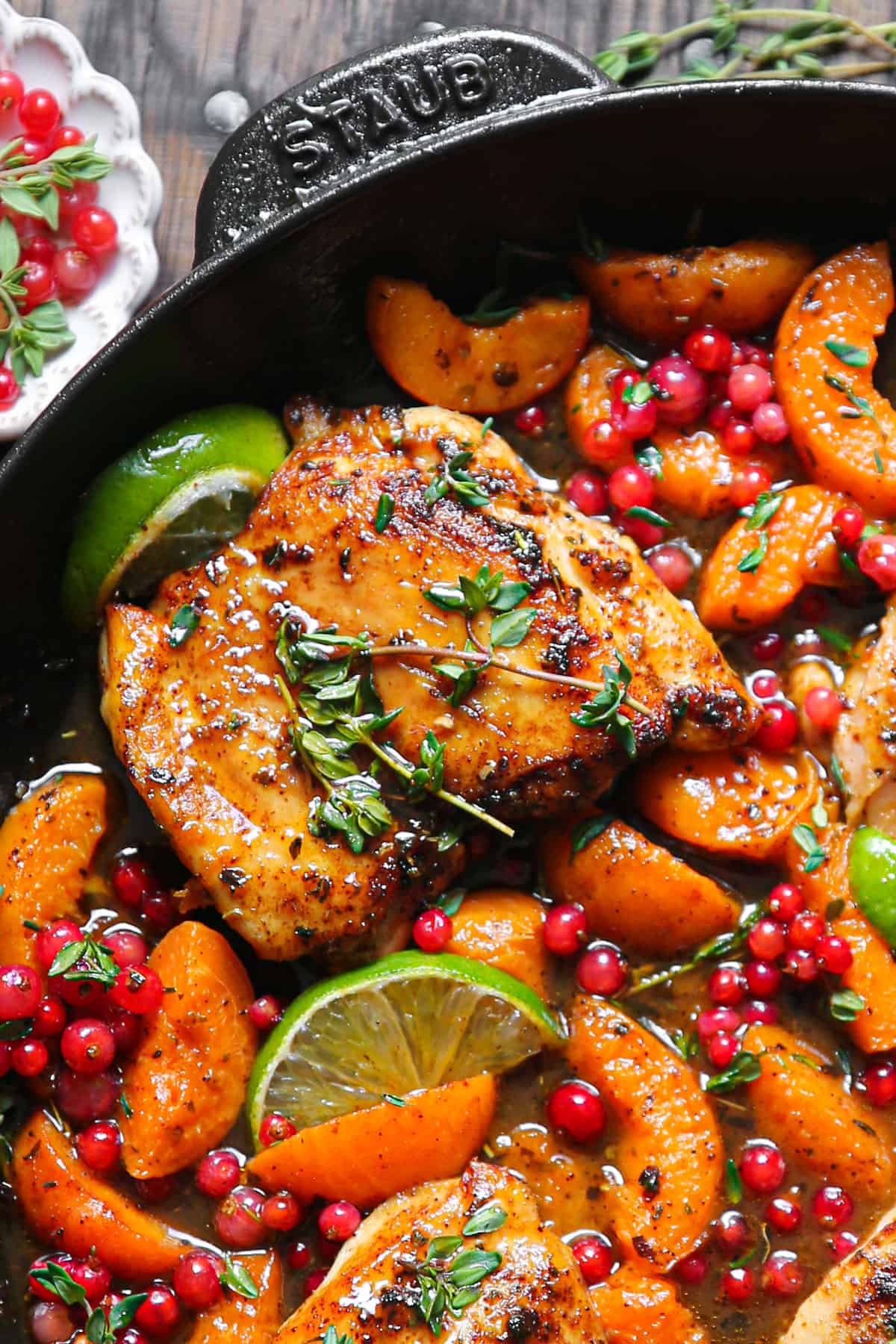 Seared Chicken Thighs with Red Currants, Apricots, Honey-Lime Sauce, garnished with lime slices - in a cast iron skillet.