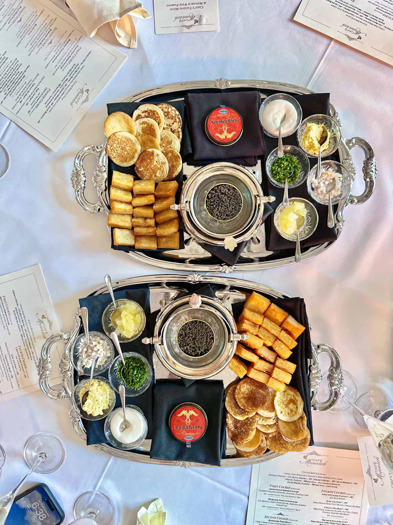 two trays with caviar and side dishes on a white linen table at Cafe Monarch in Scottsdale AZ.