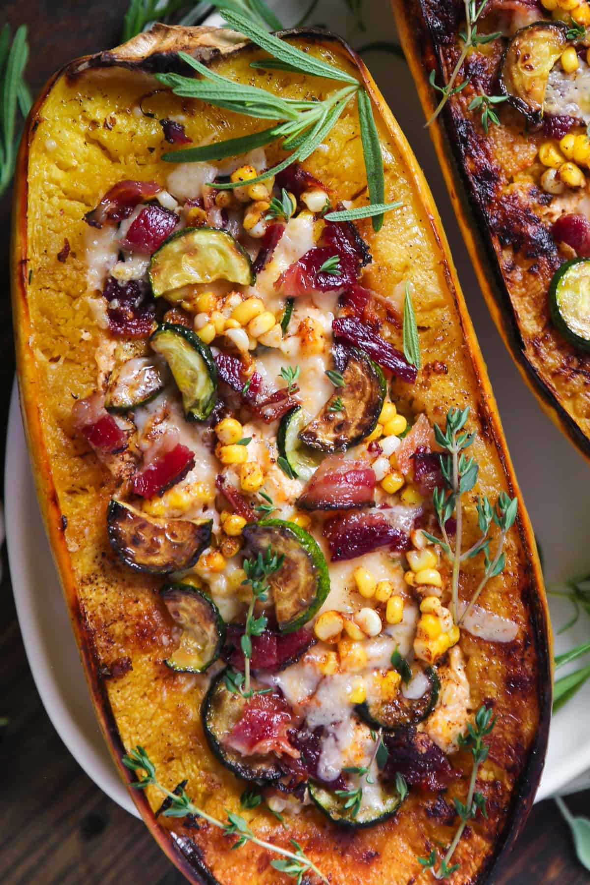 Baked Spaghetti Squash Half (one half) with Zucchini, Corn, Bacon, and Cheese mixture - on a white platter.