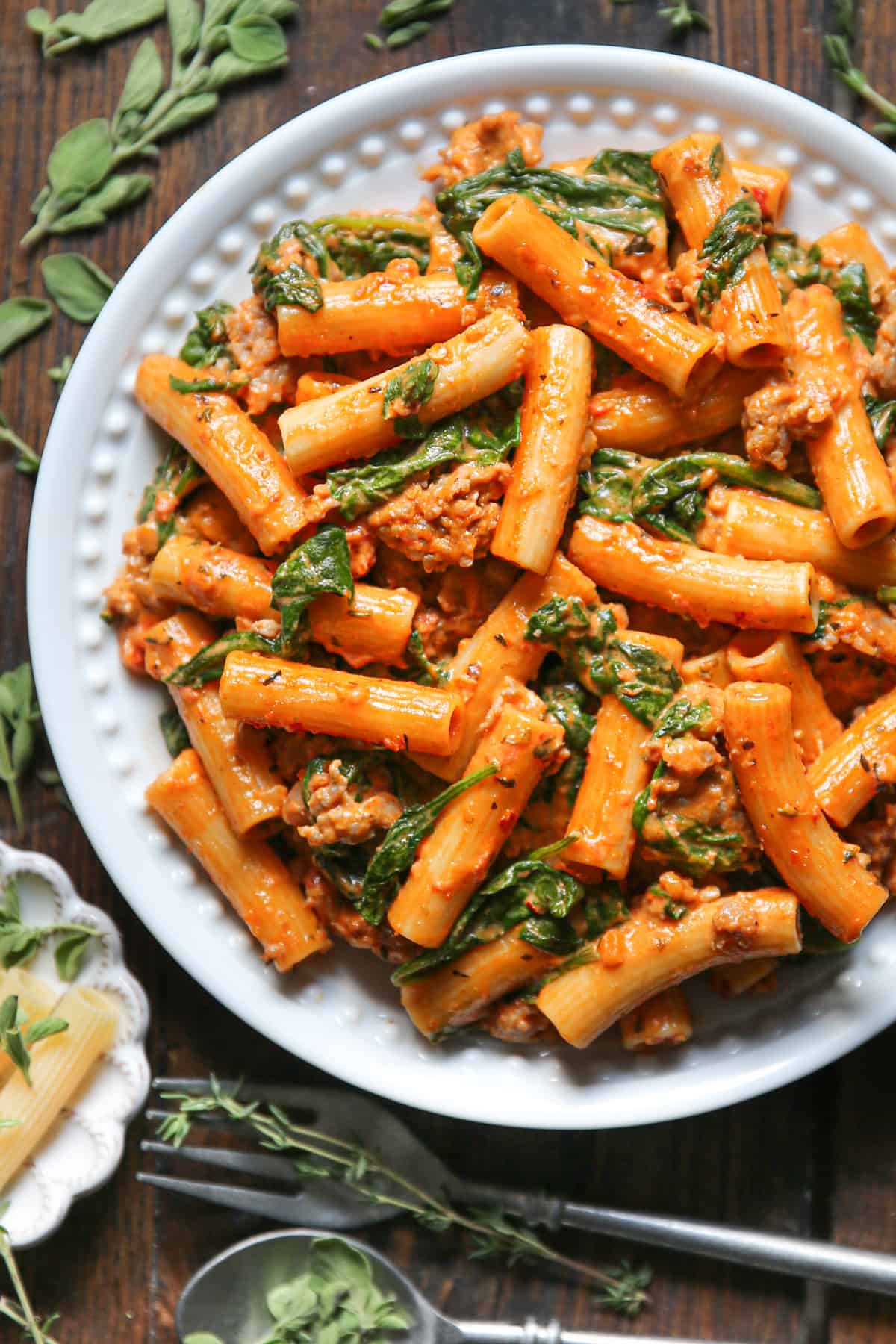 Creamy Sausage Rigatoni with Tomato Sauce and Spinach on a white plate.