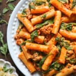 Creamy Sausage Rigatoni with Tomato Sauce and Spinach on a white plate.