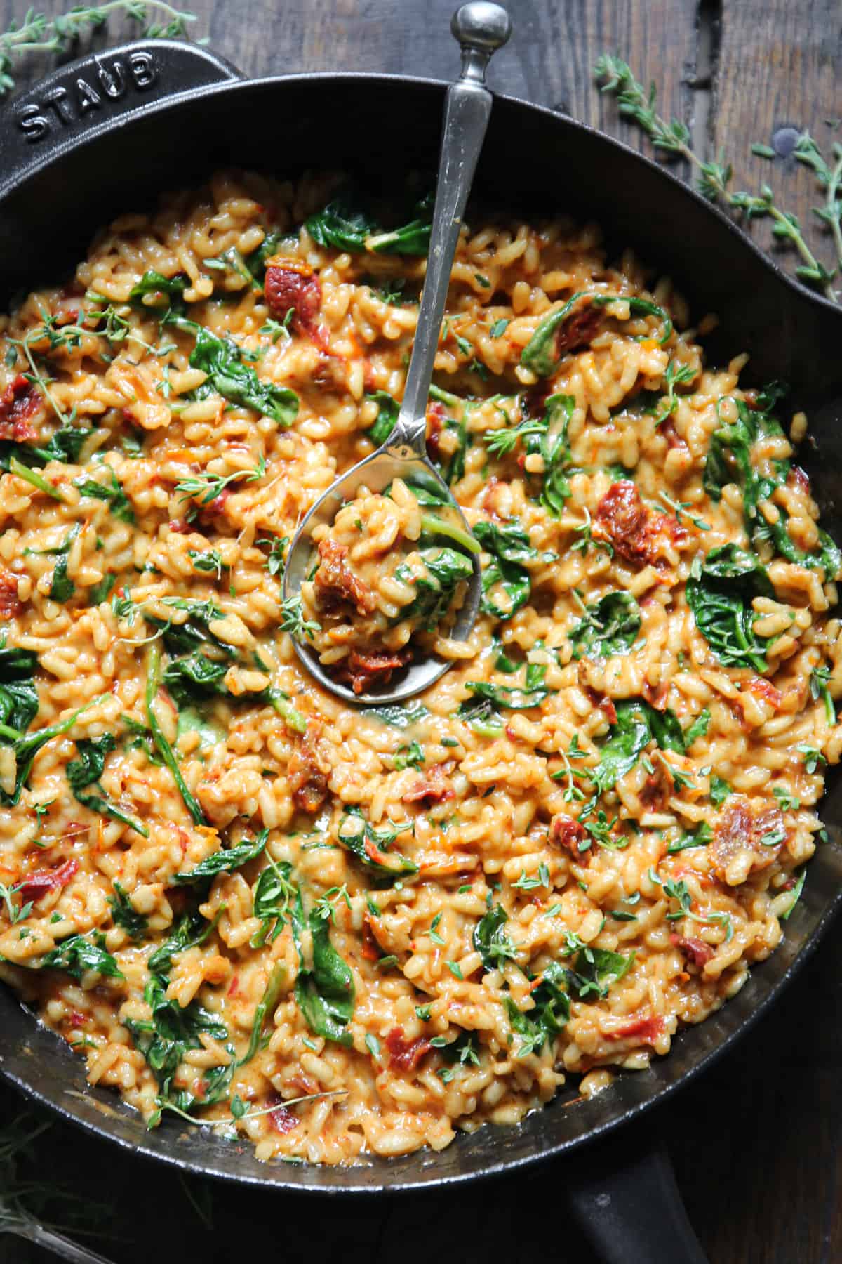Sun-Dried Tomato Risotto with Spinach with the spoon in a cast-iron skillet.