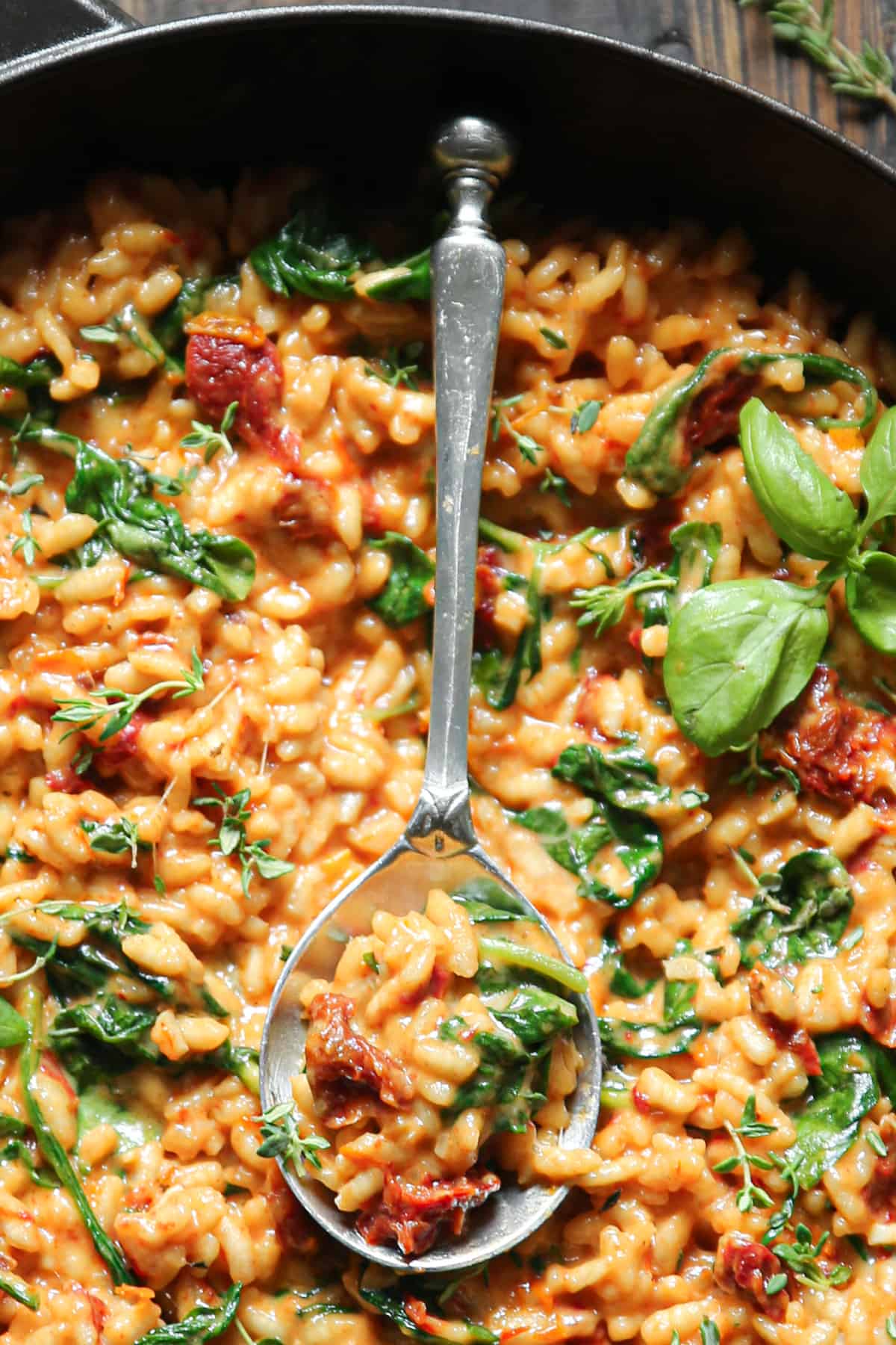 Sun-Dried Tomato Risotto with Spinach with the spoon in a cast iron skillet (close-up photo).