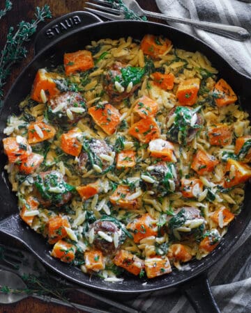 Baked Chicken Meatballs with Creamy Orzo, Roasted Cubed Butternut Squash, and Spinach - in a cast iron skillet.