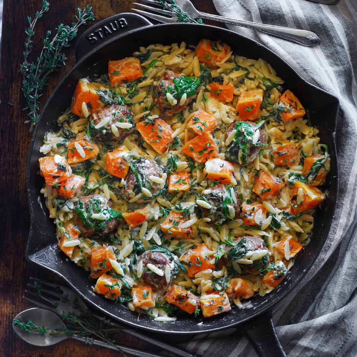 Baked Chicken Meatballs with Creamy Orzo, Roasted Cubed Butternut Squash, and Spinach - in a cast iron skillet.