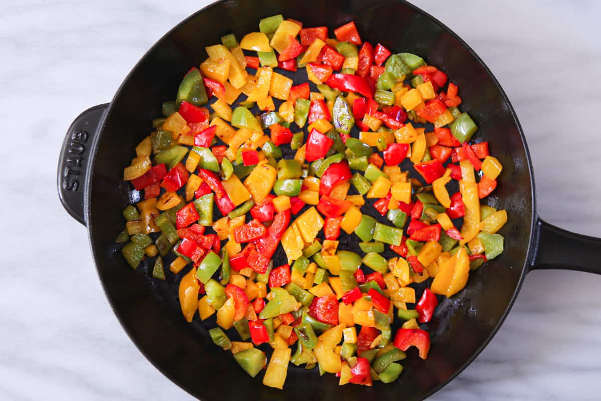 cooked chopped bell peppers in a cast iron skillet.
