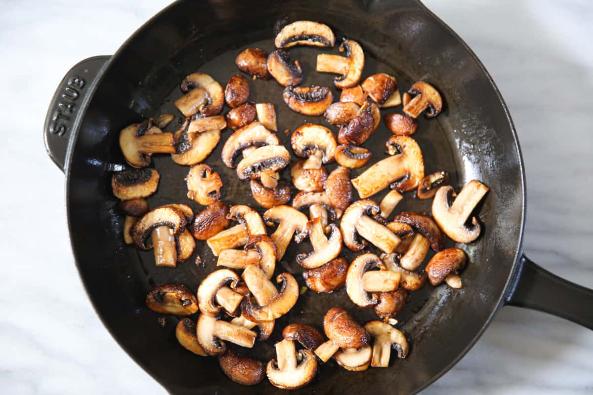 cooked sliced mushrooms in a cast iron skillet.