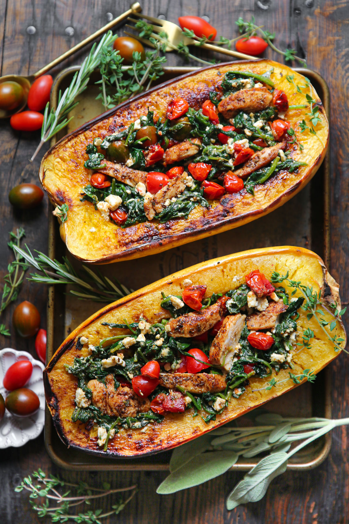 Spaghetti Squash Halves (two) stuffed with Chicken, Cherry Tomatoes, Spinach, and Feta Cheese - on a baking sheet.