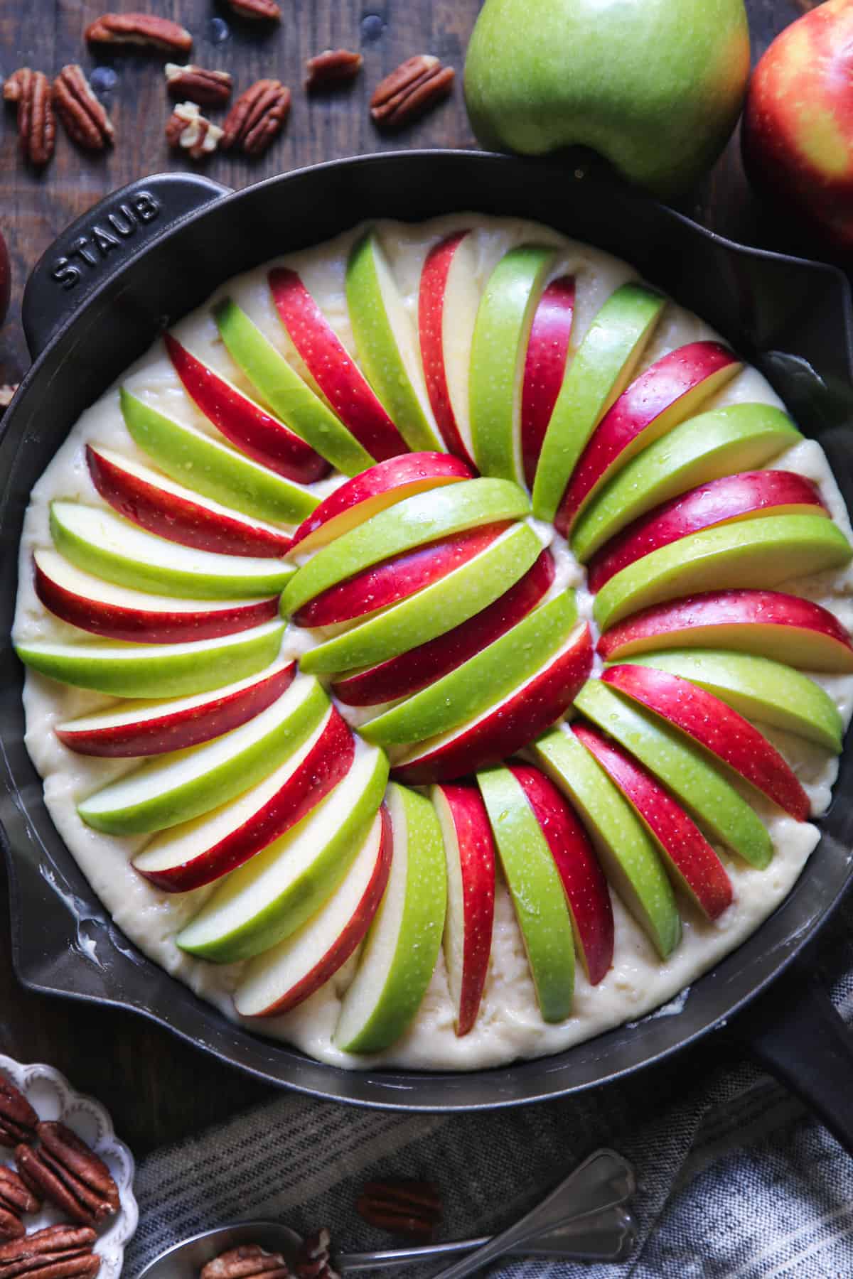 sliced apples on top of the cake batter in a cast iron skillet.