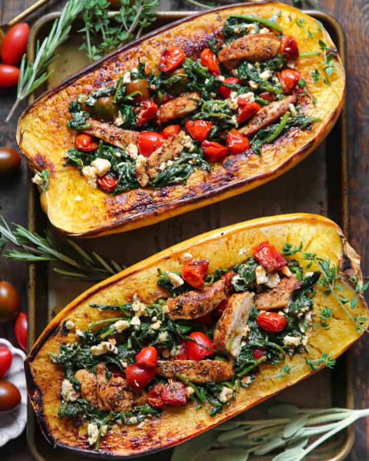 Spaghetti Squash Halves (two) stuffed with Chicken, Cherry Tomatoes, Spinach, and Feta Cheese - on a baking sheet.