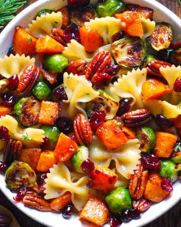 Butternut Squash Pasta Salad with Brussels Sprouts, Pecans, and Cranberries in a white bowl.