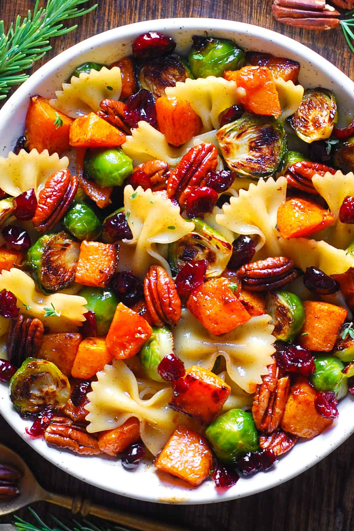 Butternut Squash Pasta Salad with Brussels Sprouts, Pecans, and Cranberries in a white bowl.